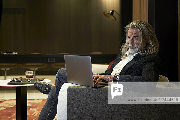 Businessman using laptop while sitting on sofa in hotel