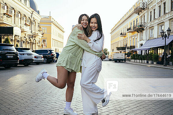 Happy female friends hugging each other in city