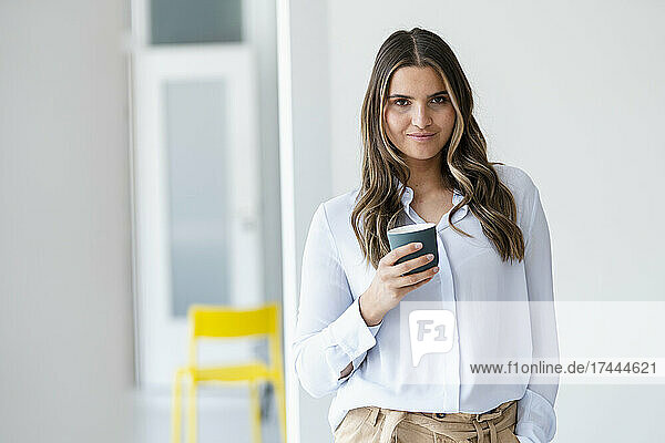 Female business professional holding coffee cup in office