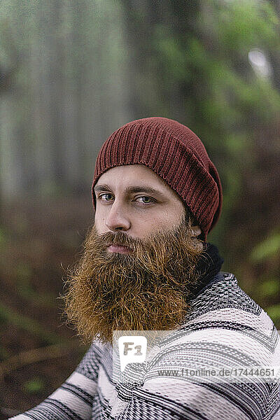 Bearded young man with knit hat at woodland