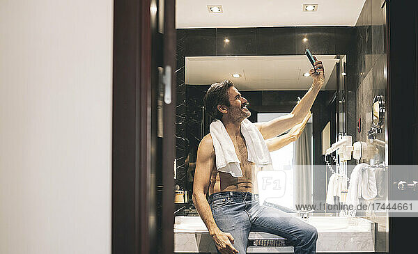 Smiling sman taking selfie through mobile phone in hotel room