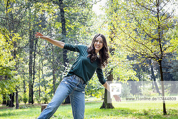 Happy woman with arms outstretched at park