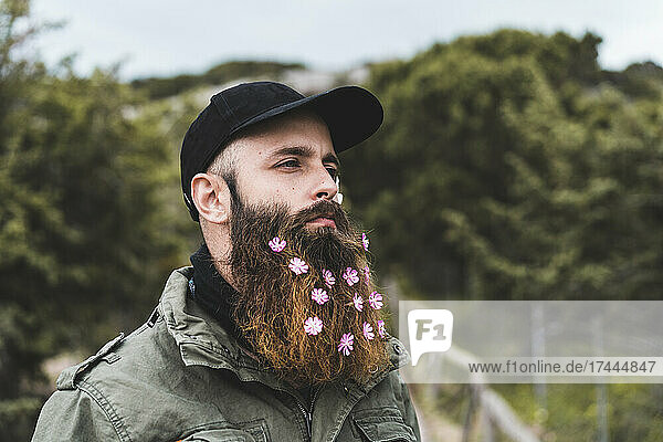 Hipster man with flowers in beard wearing cap