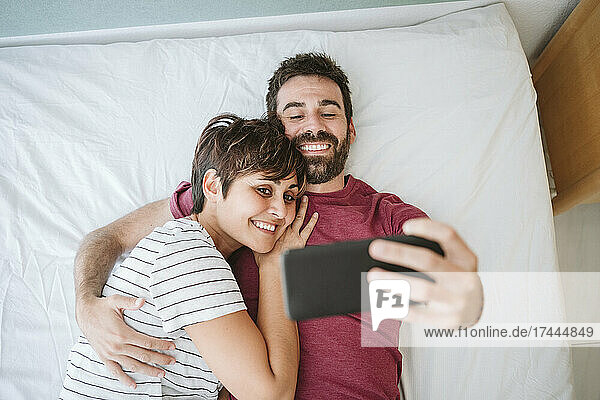 Mann und Frau machen ein Selfie über ihr Smartphone  während sie im Bett liegen