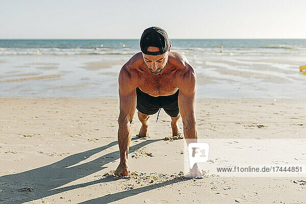 Man wearing cap exercising on beach during sunny day