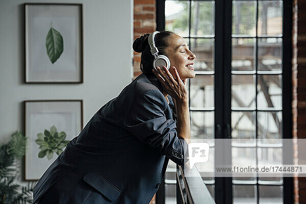 Geschäftsfrau mittleren Alters hört im Büro Musik über Kopfhörer