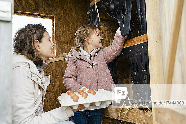 Smiling mother and daughter with egg carton in organic farm