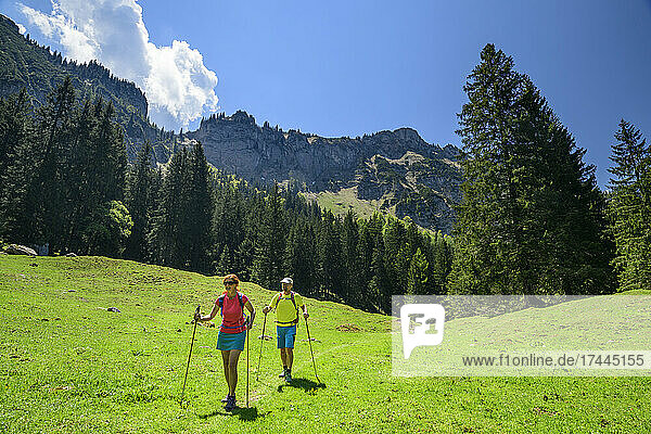 Male and female tourists hiking on green landscape during vacations