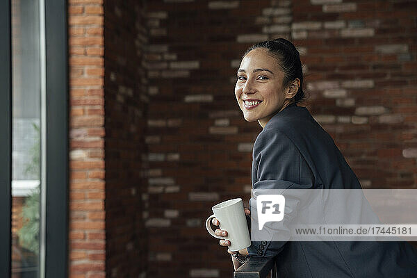 Smiling businesswoman with coffee cup in office
