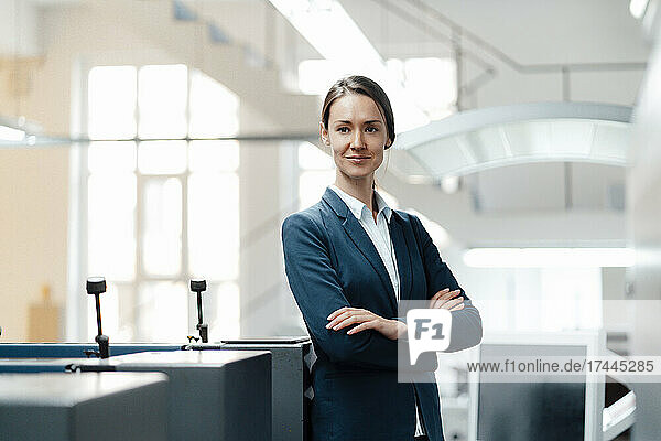 Confident female professional standing with arms crossed in industry