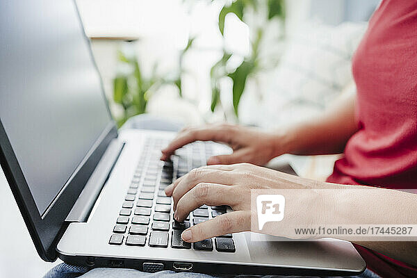 Woman typing while using laptop at home