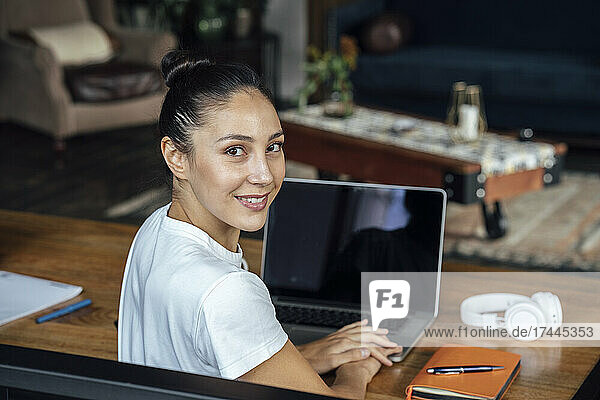 Smiling businesswoman with laptop on desk