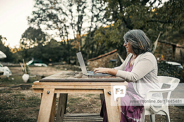 Campingfrau benutzt Laptop am Tisch sitzend