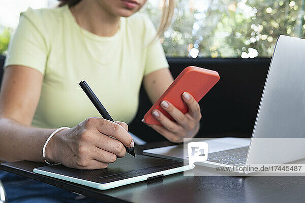 Woman with digitized pen writing in graphic tablet