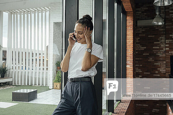 Smiling mid adult businesswoman talking on mobile phone in office