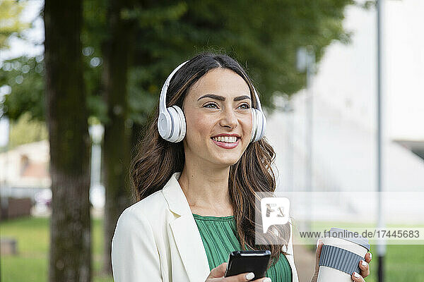 Happy woman listening music through wireless headphones
