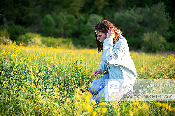 Portrait of confident young woman sitting in field