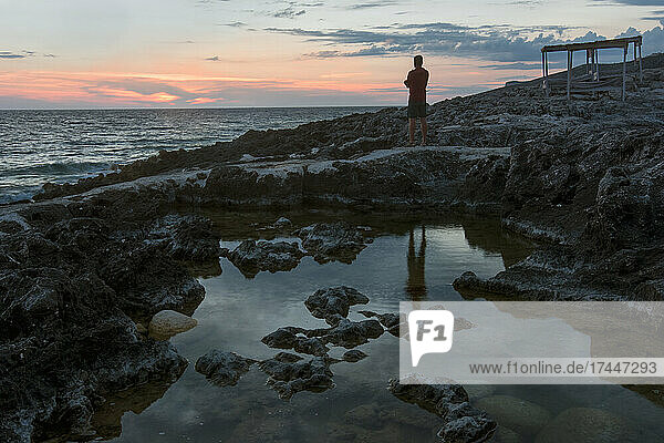 Adult man watching the sunset over Porto Roxa  Zakynthos island