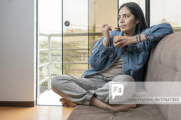 Woman eating homemade cashew butter sitting on a sofa