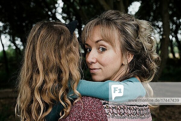 portrait of mother looking back whilst holding daughter