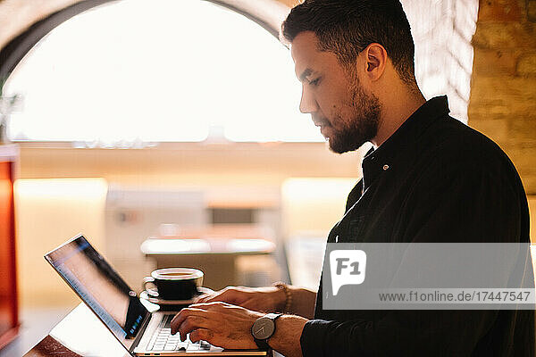 Serious man using laptop computer at cafe