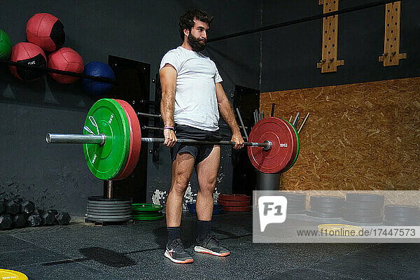 Young bearded man doing deadlift exercise in a crossfit gym.