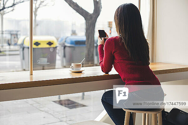 Girl typing a message on her mobile phone while having a coffee