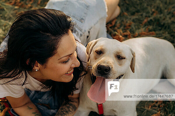 Happy woman hugging her Labrador puppy outdoors