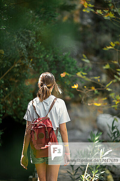 Female tourist with a backpack travels through the forest