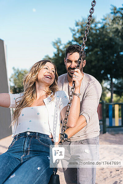Married couple playing on the swing in a park
