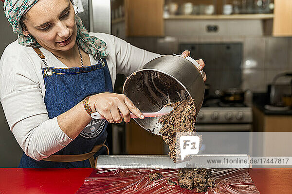 Female cook removing the mixture of ingredients from a pot on a film