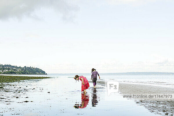 Wide angle view of two girls exploring the beach at Carkeek Park