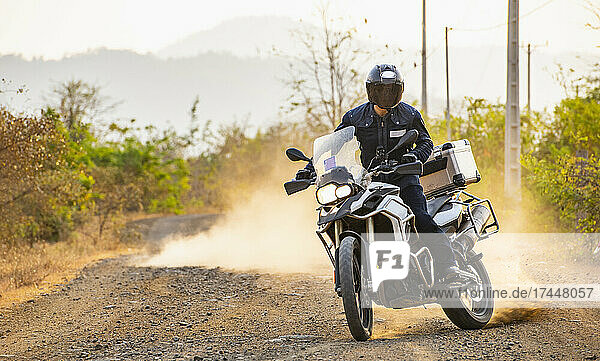 Man riding his adventure motorbike on dirt road in Cambodia
