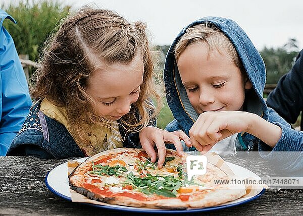 girl and boy sharing a pizza together at an outdoor restaurant