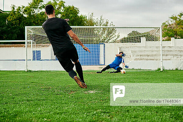 A goalkeeper saves a penalty shooting by a soccer player