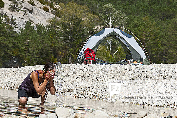 Woman washing her face at remote camp site in the Verdon canyon