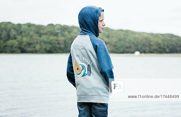 boy stood looking thoughtful on his own at the coast