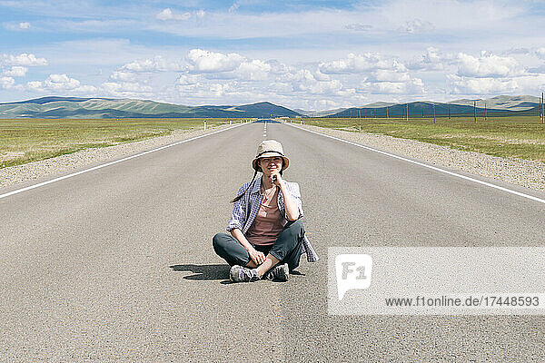 Woman traveler sitting on the mountain road. Altai republic.