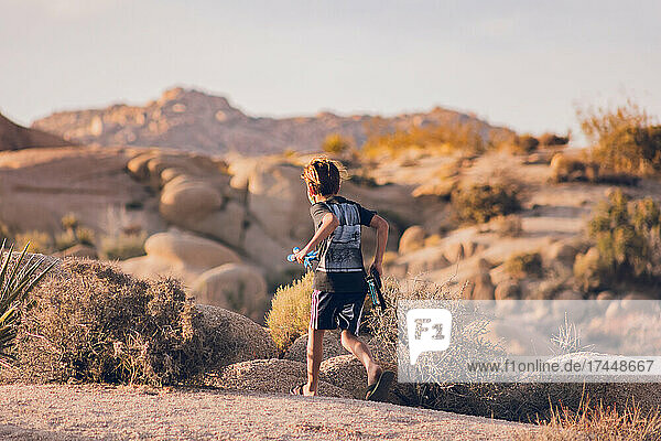 Boy running in the desert with a bow and arrow.