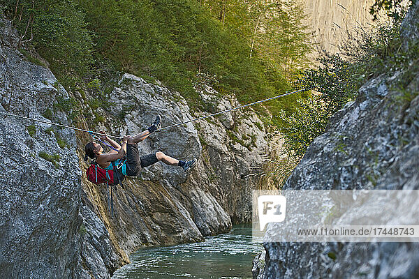 Woman crossing river on Tyrolean traverse in the Verdon canyon