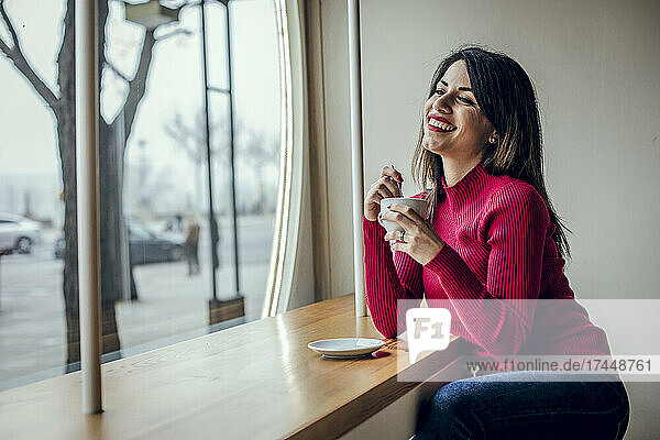 Brunette woman drinking coffee while smiling