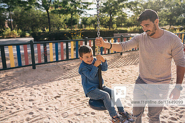 Father and his son playing with a zip line in a park