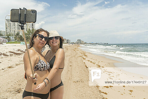 Mother and daughter on the beach taking a photo with their smartphone