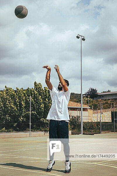 Young boy playing on a court while shooting basketball to basket