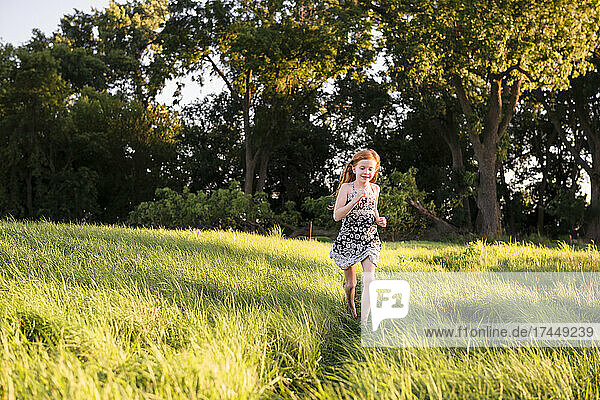 Young girl running through tall grass in country setting.