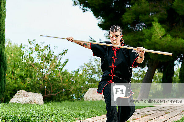 Woman in uniform practicing martial arts with a stick
