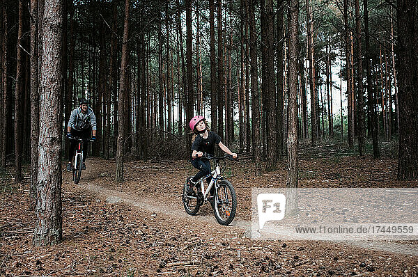 dad and daughter riding their bikes through a forest