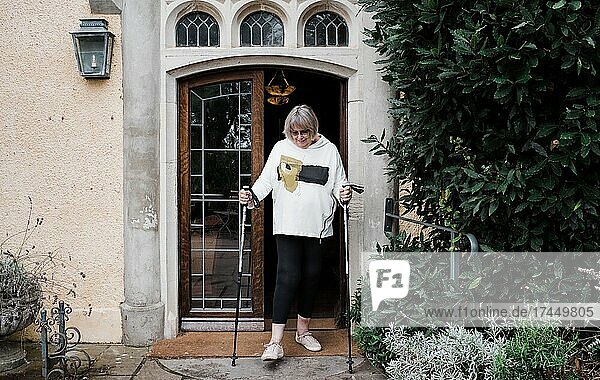 woman with walking sticks through a door of a country home