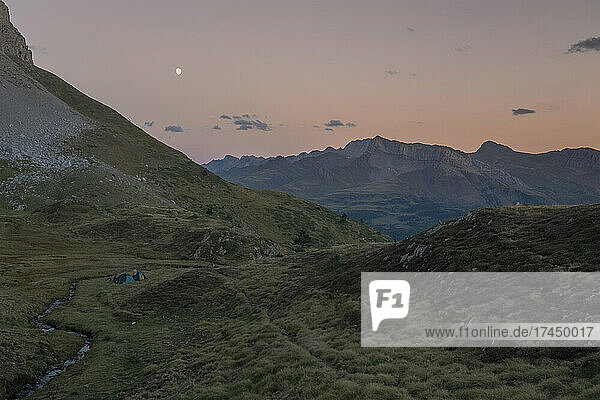 Group of people with tents watching sunset and moon rise  The Pyrenees