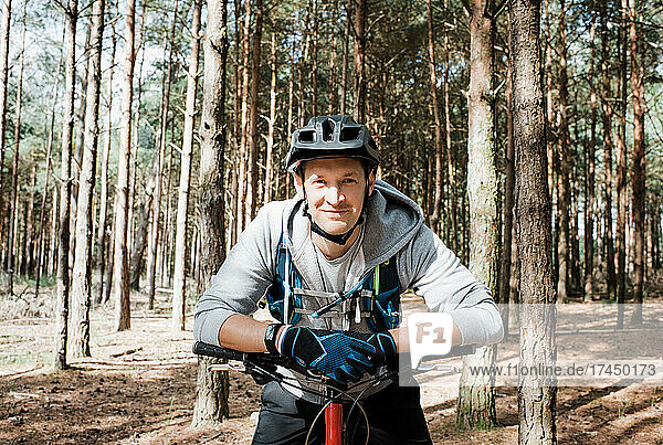 portrait of man leaning on his bike whilst cycling in the forest